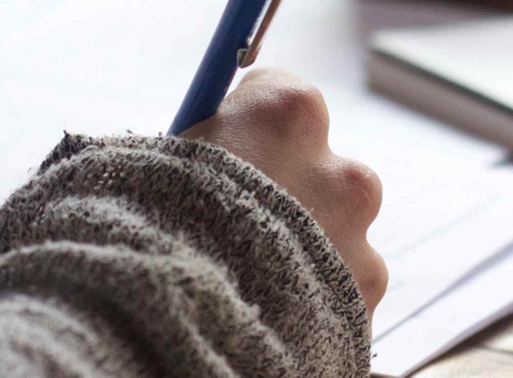 Hand writing on white paper with a blue pen. 